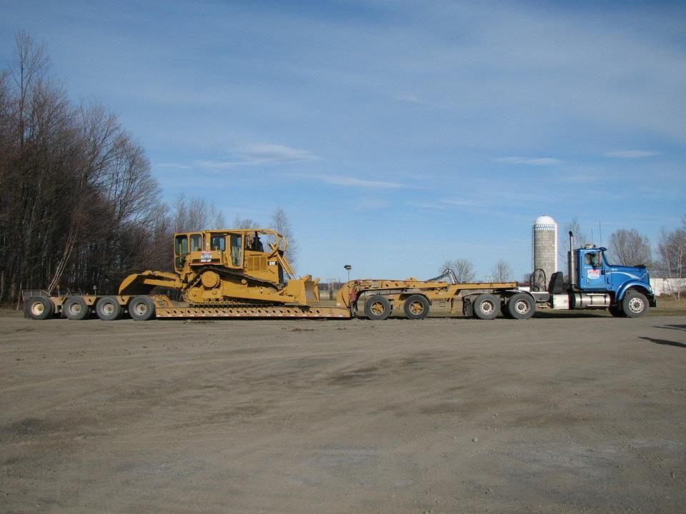 Un bulldozer est transporté sur une remorque à plateau.