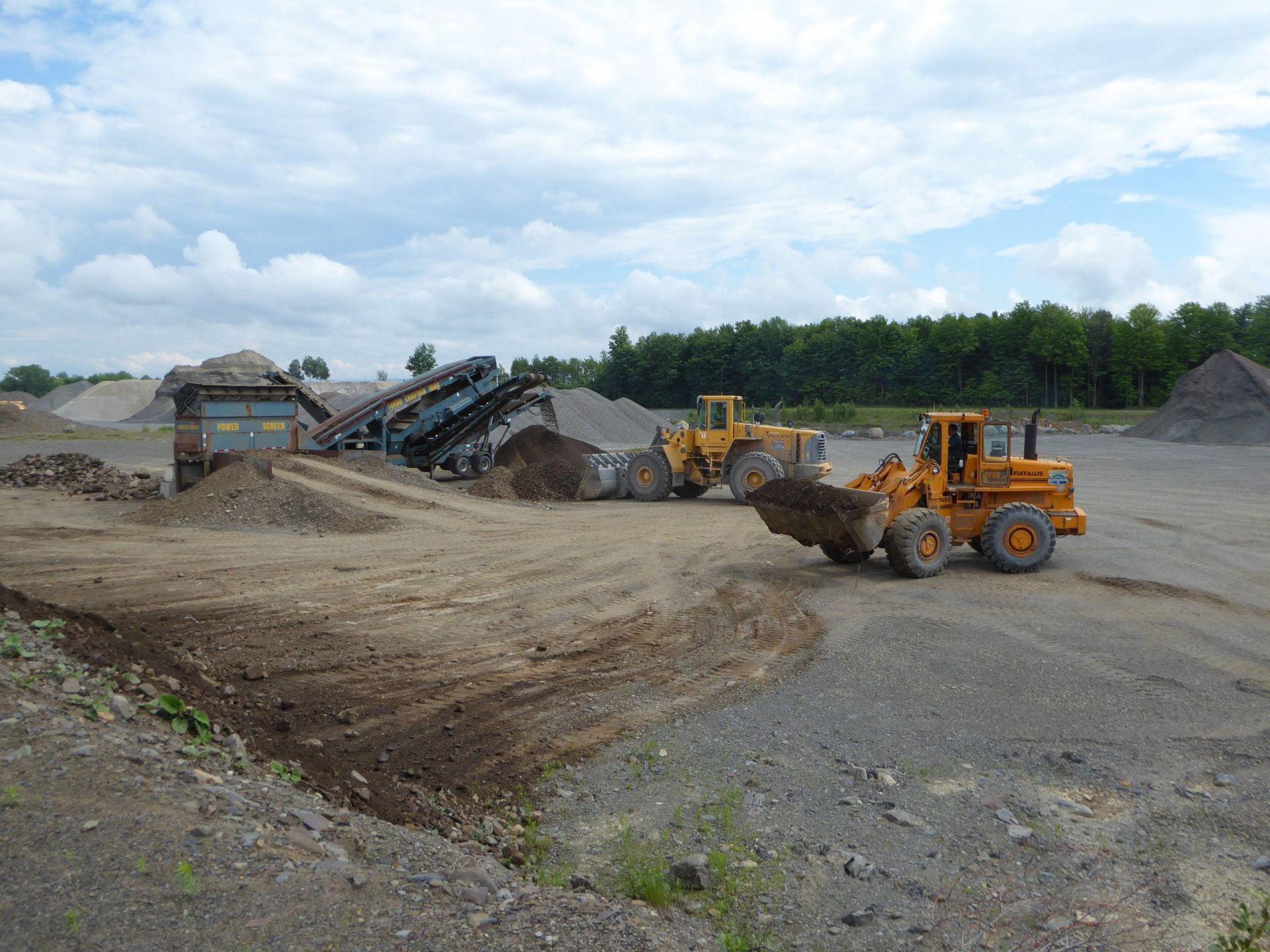 Deux bulldozers déplacent de la terre dans un champ de terre