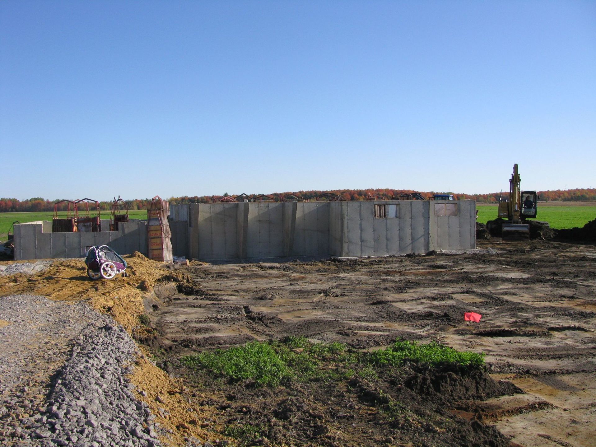 Un grand mur de béton est en cours de construction dans un champ de terre.