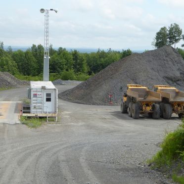 Deux camions à benne basculante sont garés sur le bord d'un chemin de terre