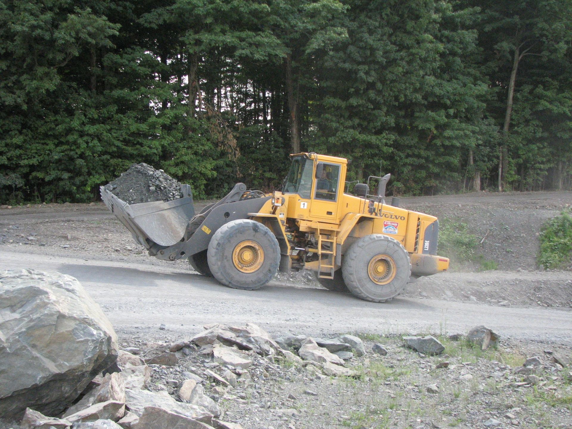 Un bulldozer jaune roule sur un chemin de terre.