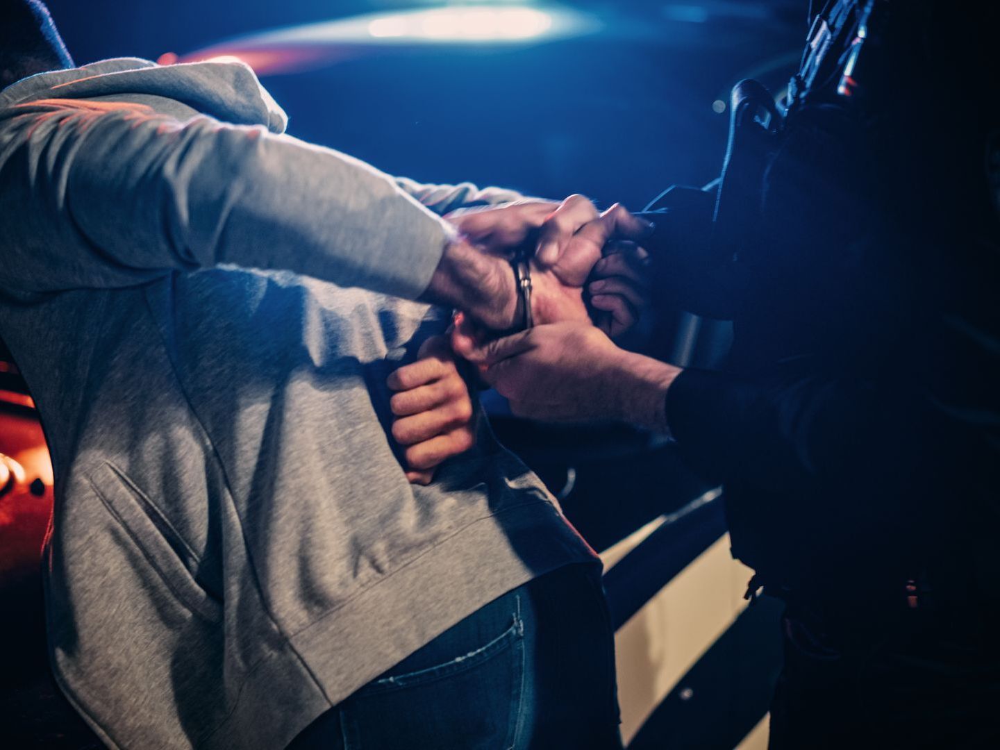 mans hands being cuffed behind back by officer