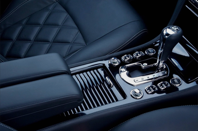 Close-up of a luxury car's interior. Black leather, chrome details, gear shift and console.