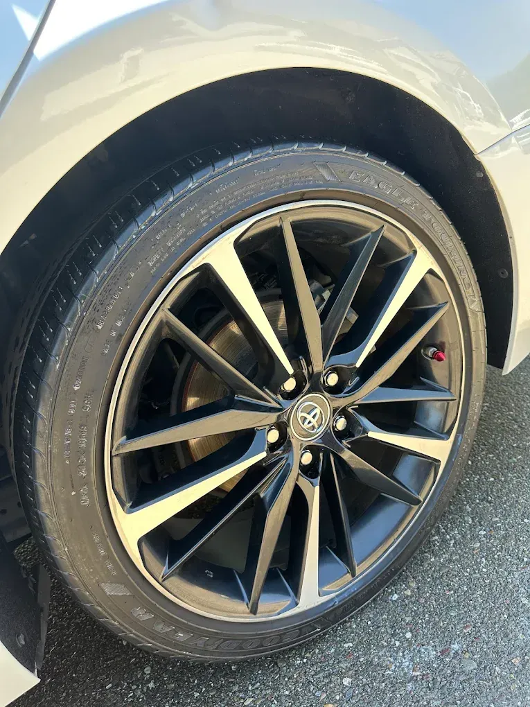 Car's wheel with black and silver rims, black tire, and red valve cap.