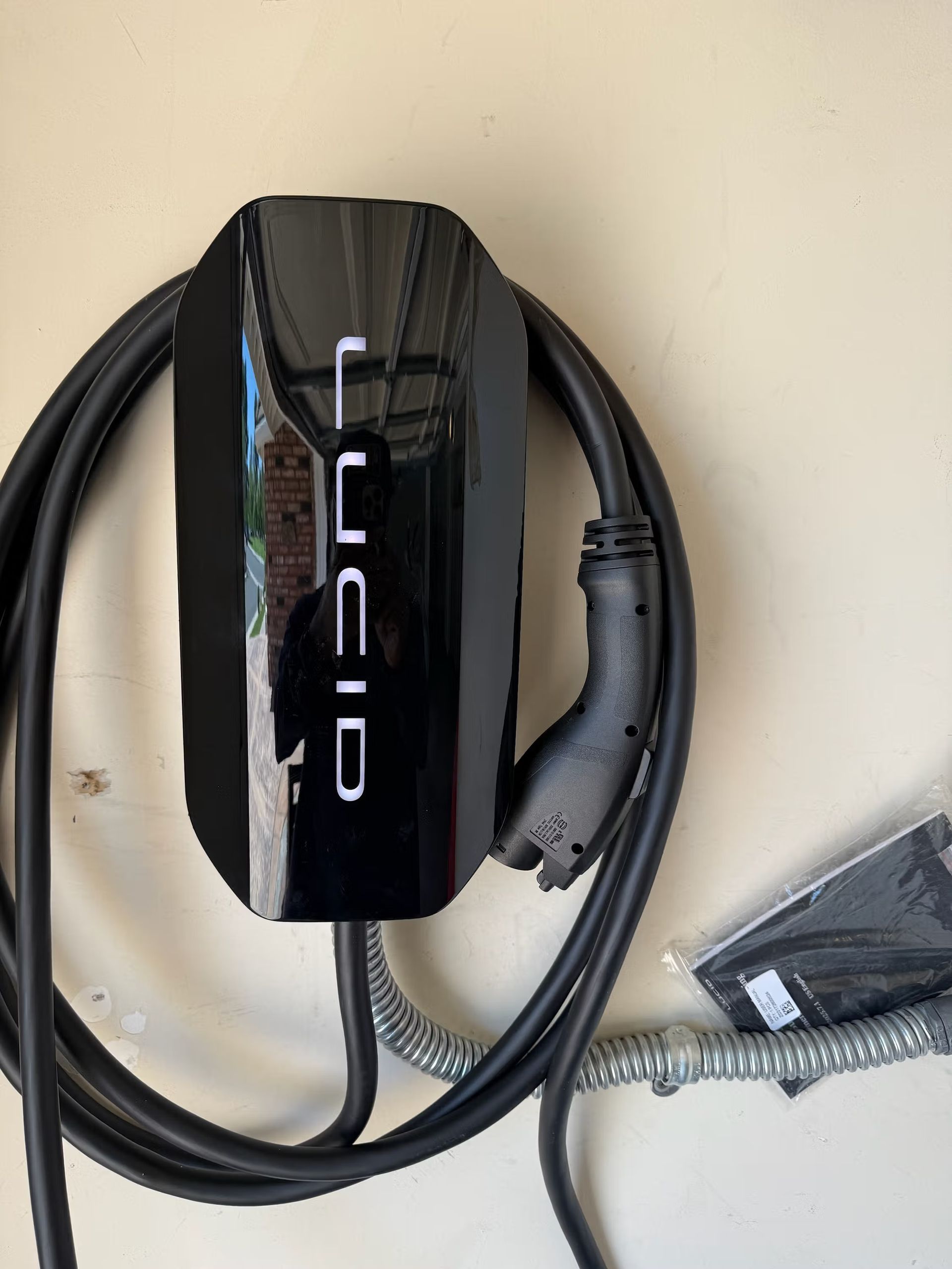 Lucid EV charger mounted on a wall with black cable and plug.