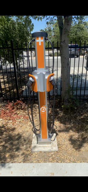 Orange and silver electric vehicle charging station with two nozzles.
