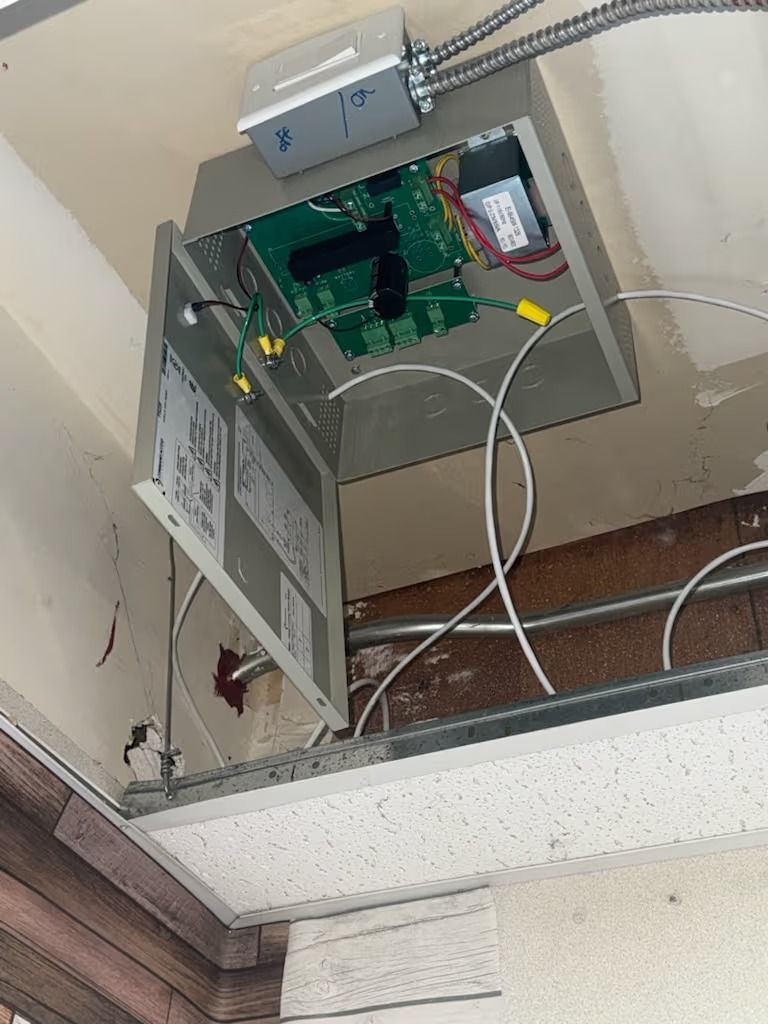 Open electrical box mounted on a ceiling. Wires and circuit board are visible.