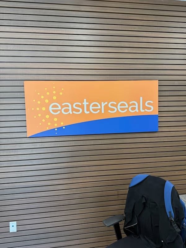 Easterseals sign with orange and blue background on a brown-striped wall.
