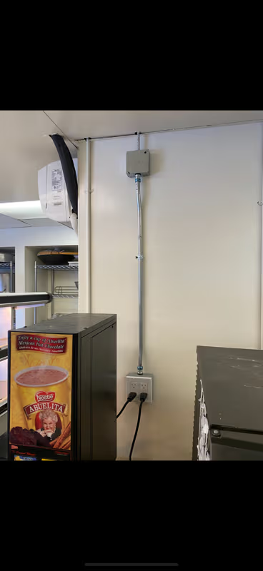Electrical conduit on a white wall with outlets. Coffee machine and another appliance with cords plugged into the outlets.