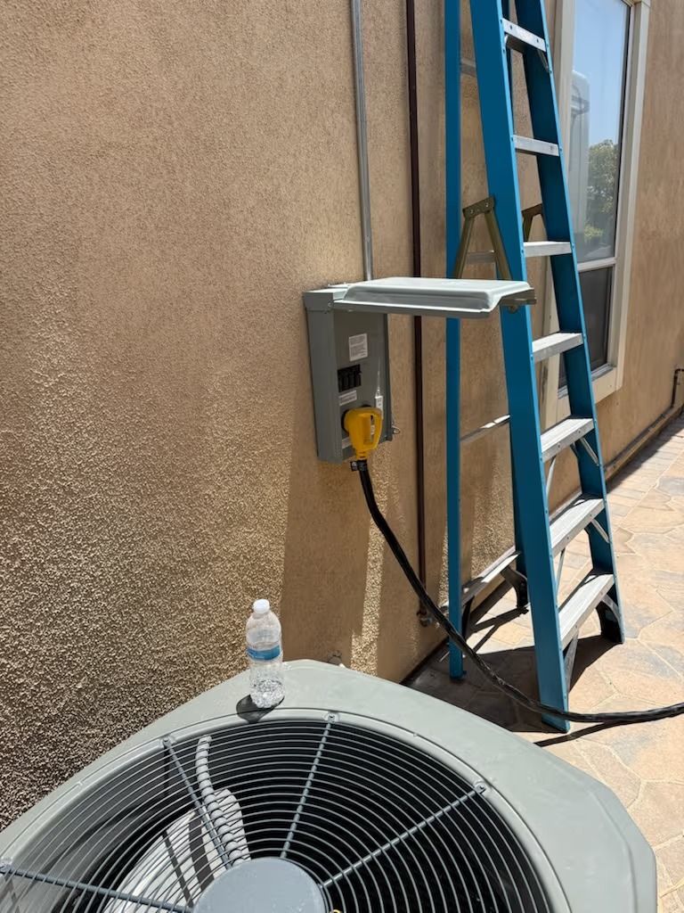 Air conditioning unit next to electrical box, ladder, and wall. A water bottle rests on the unit.