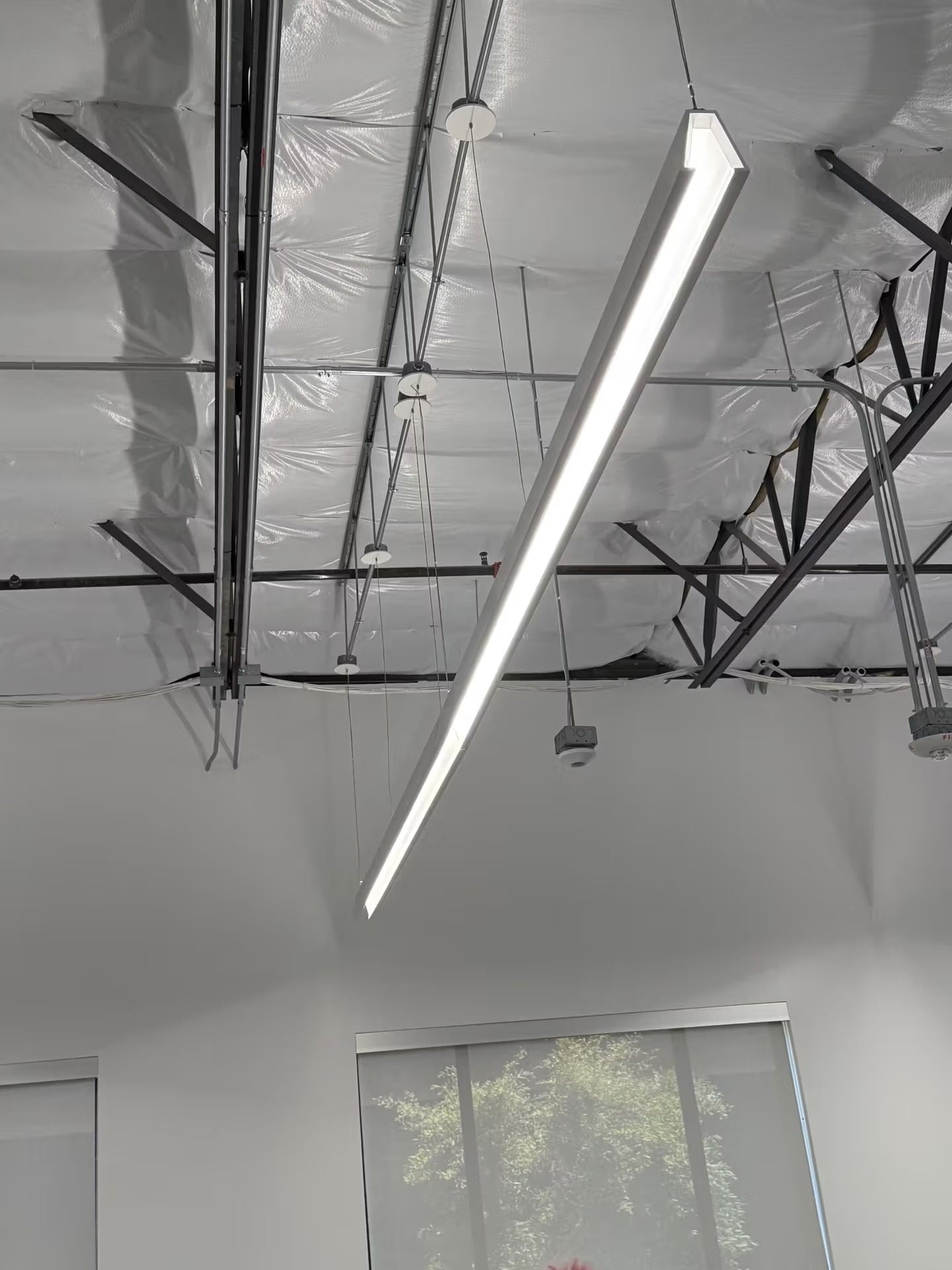 Long, rectangular LED light fixture suspended from a high ceiling.
