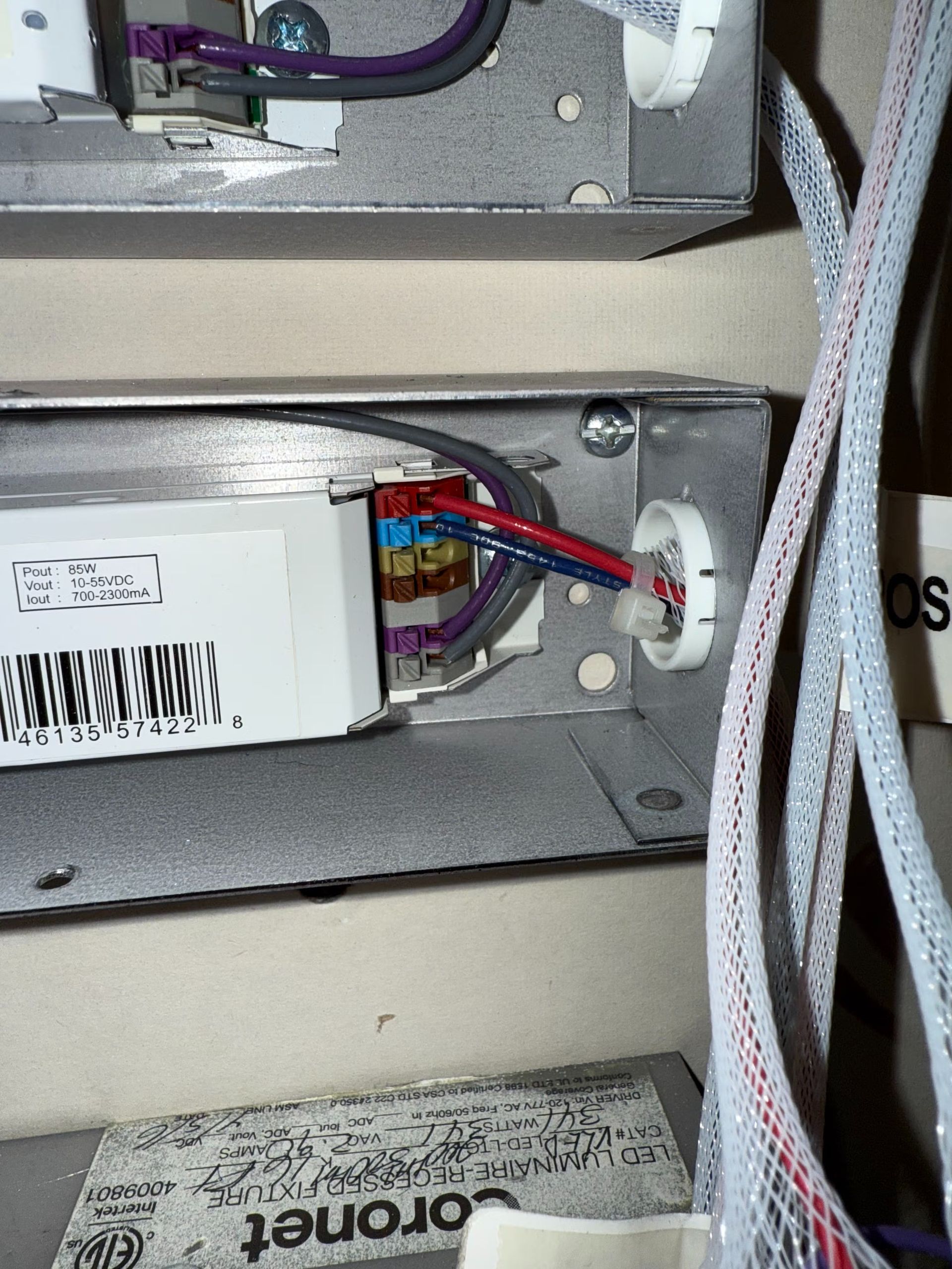 Fluorescent light fixture wiring inside a metal box on a wall, with visible wires and a barcode.