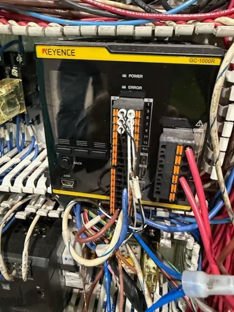 Keyence PLC in an electrical panel with various wires and terminals.