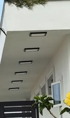 White building exterior with six rectangular lights installed in the overhang.