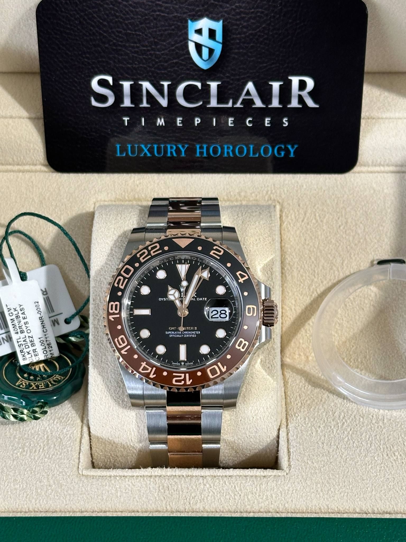 A rolex watch is in a green box on a table.