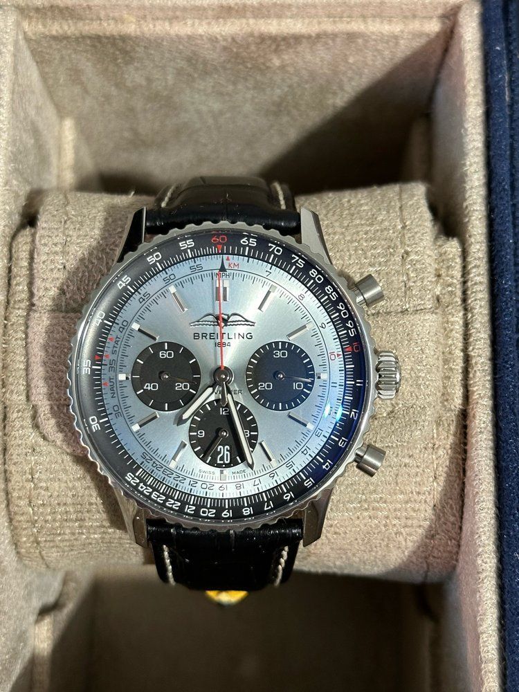 A breitling watch is sitting on a wrist in a box.