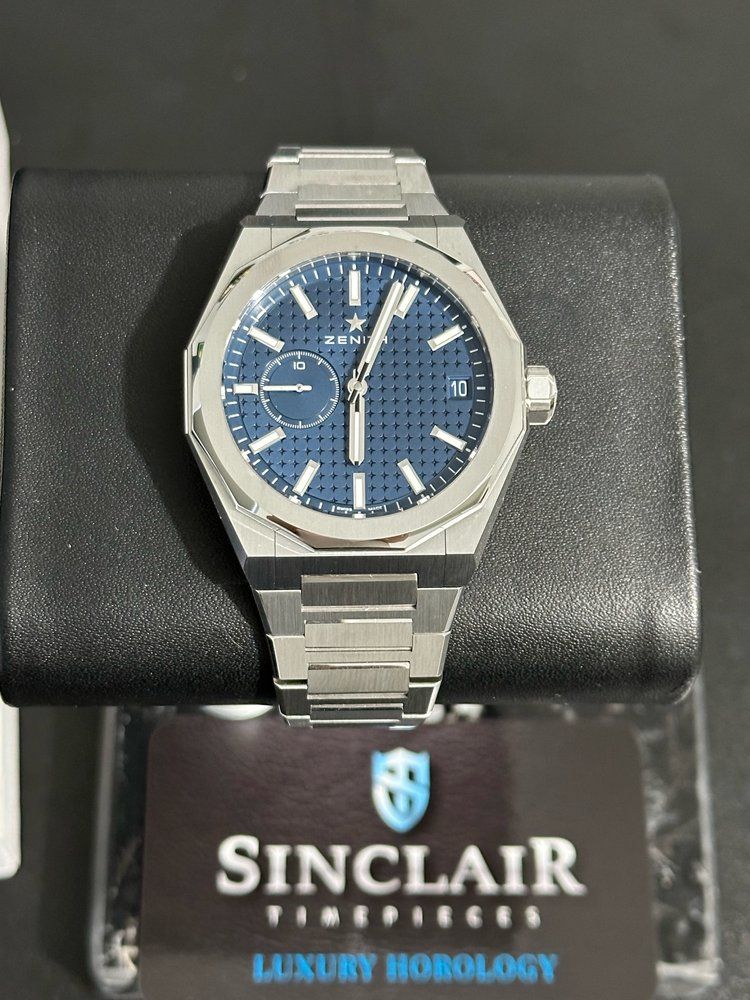 A sinclair watch is sitting on a black cushion