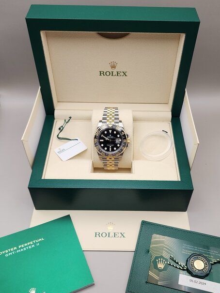 A rolex watch is in a green and white box.