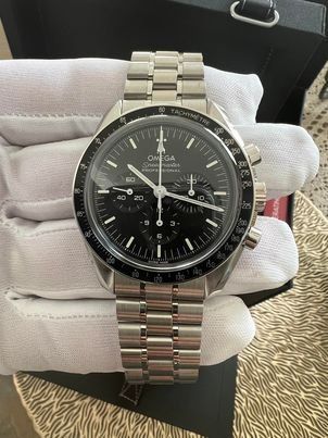 A person is holding a stainless steel watch in their hand.
