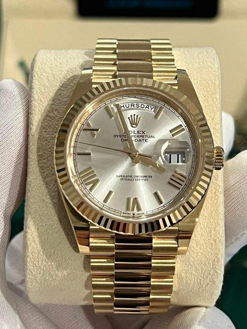 A person is holding a gold rolex watch in their hand
