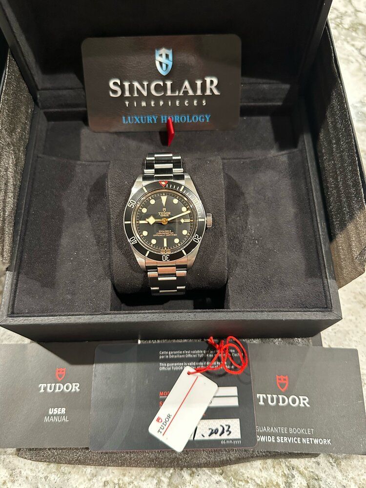 A tudor watch is in a box with a certificate.