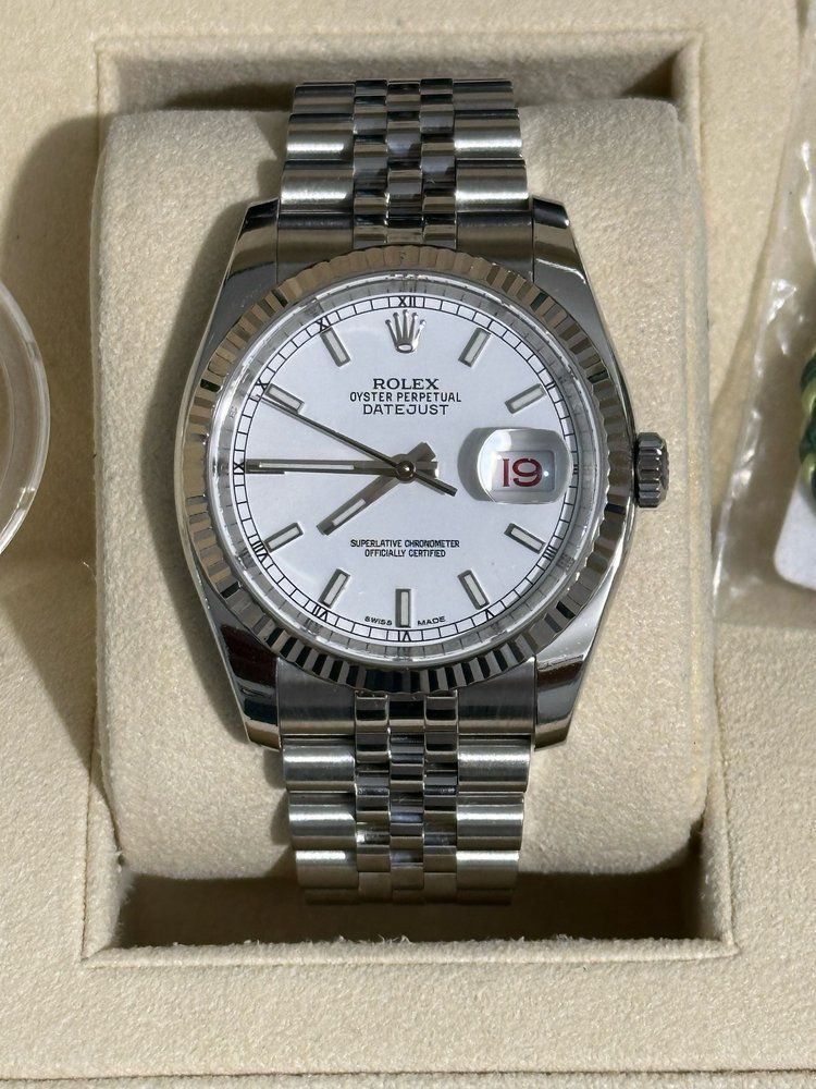 A silver rolex watch with a white face and silver band
