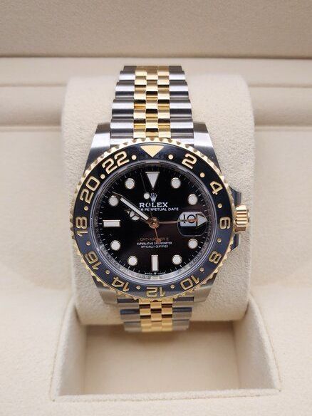 A rolex watch with a black face and gold band