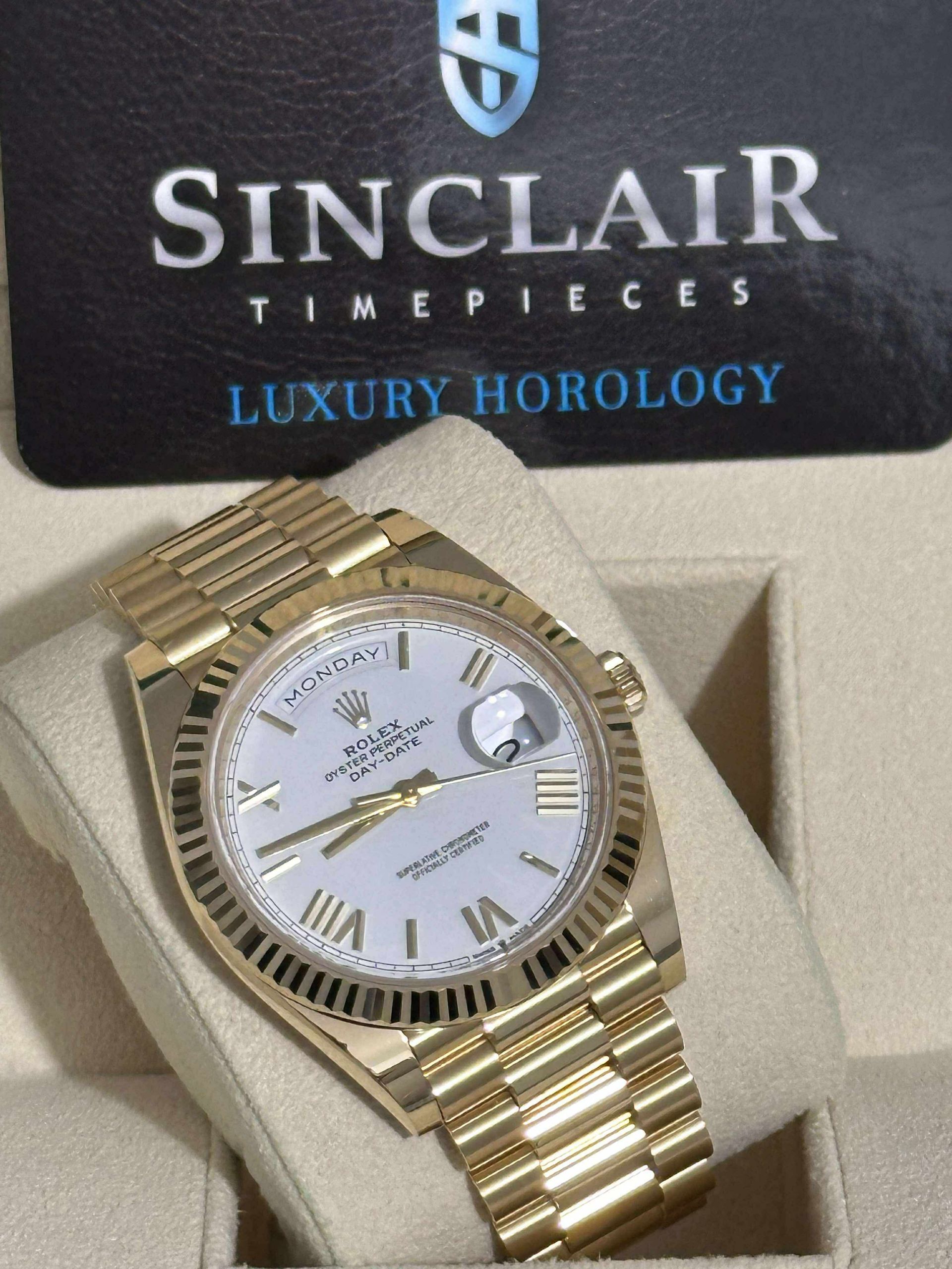 A rolex watch is in a green box with a sinclair card