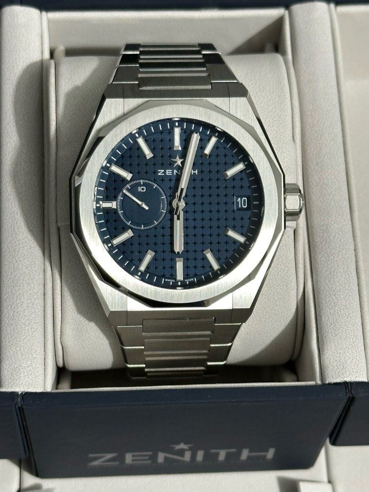 A zenith watch sits in a white box