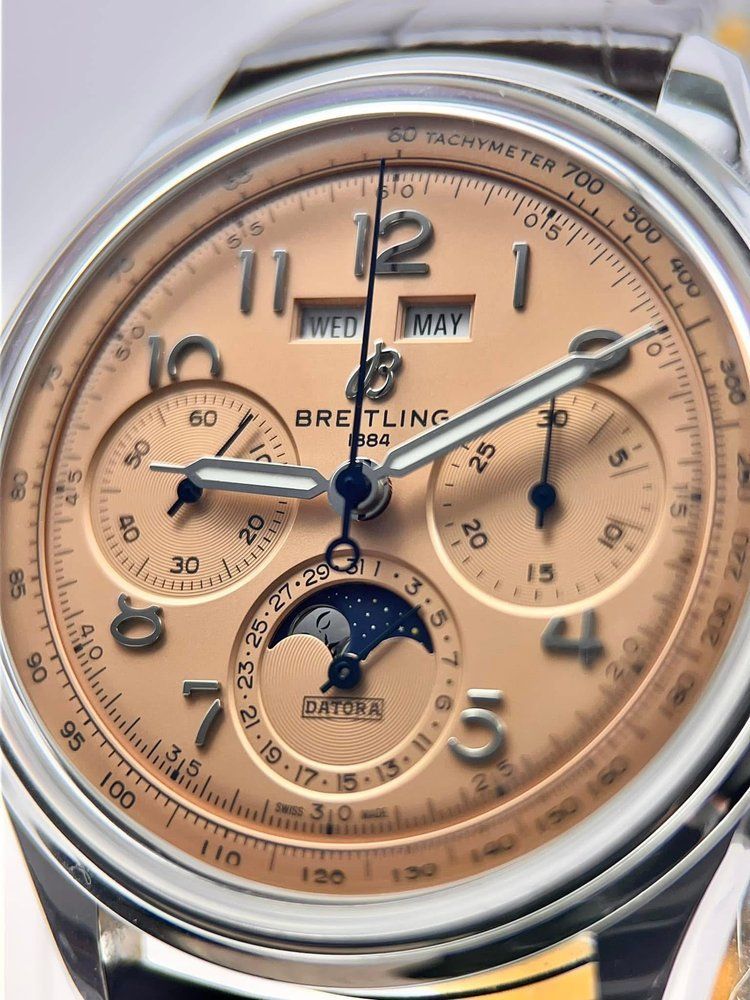 A close up of a breitling watch with a tan face