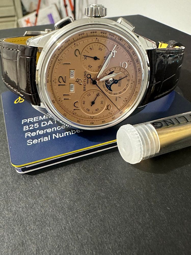 A watch is sitting on top of a piece of paper next to a tube.