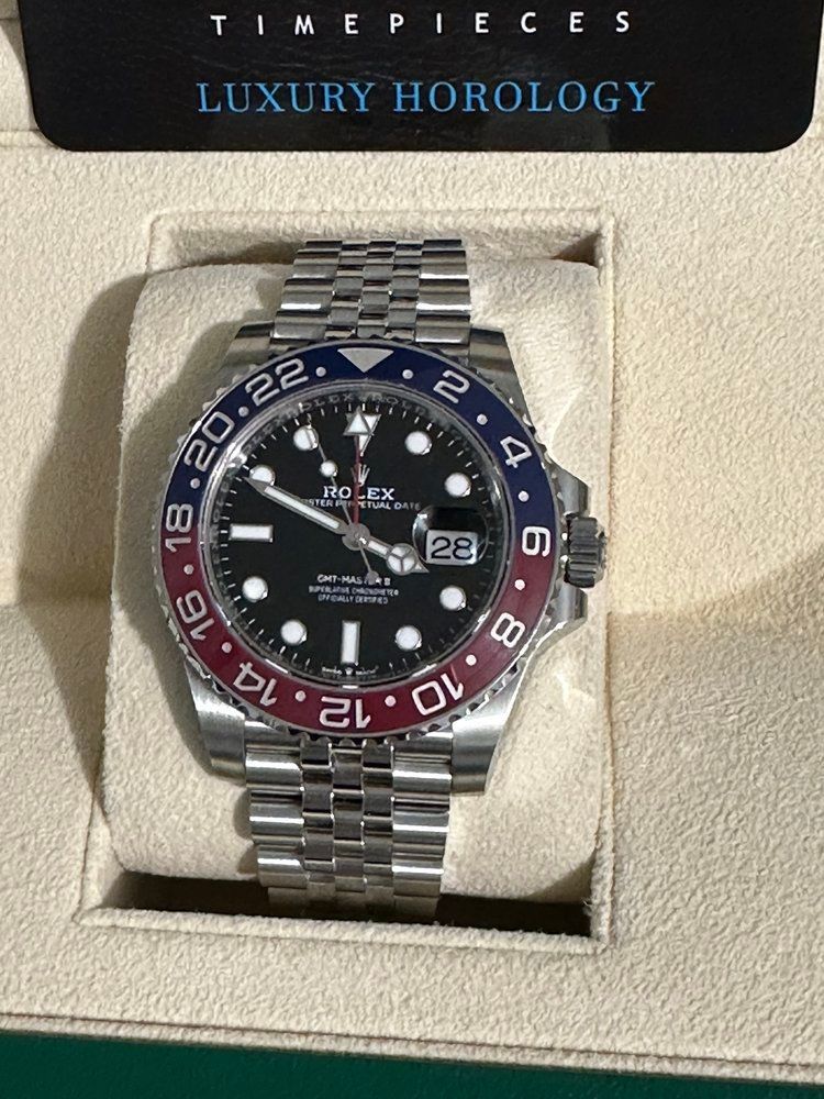 A rolex watch is sitting on a white cushion in a box.