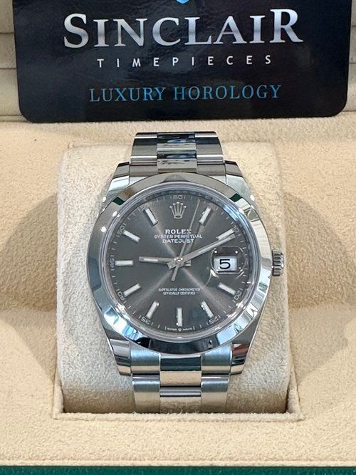 A rolex watch is sitting on top of a white cushion.