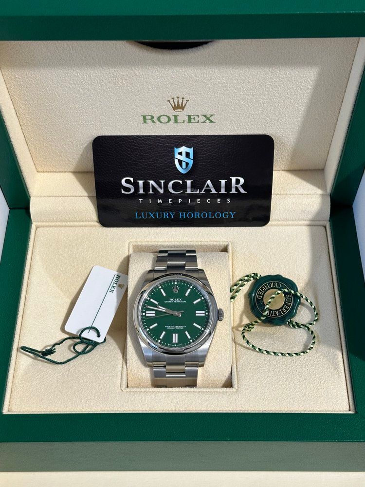 A rolex watch with a green face is in a box