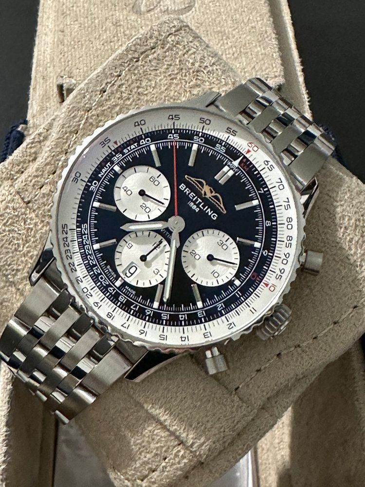 A breitling watch is sitting on top of a white cloth.