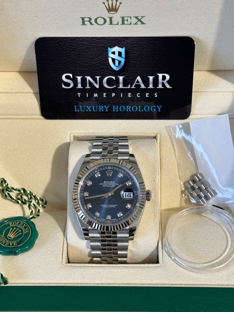 A rolex watch is in a box next to a sinclair timepieces card