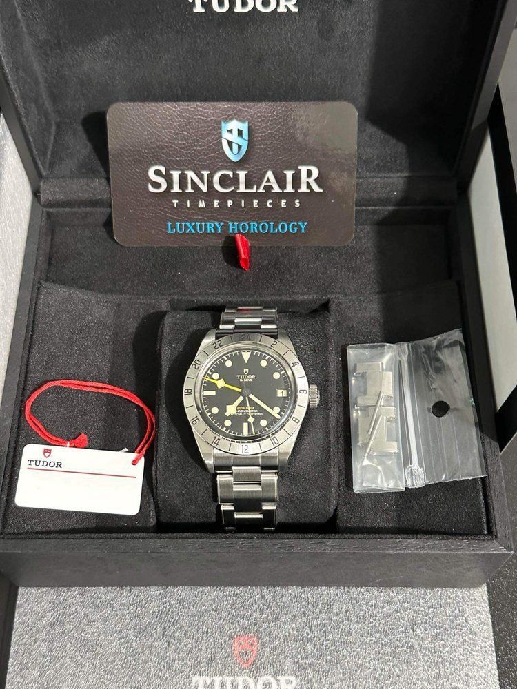 A tudor watch is in a black box with a card on top of it.
