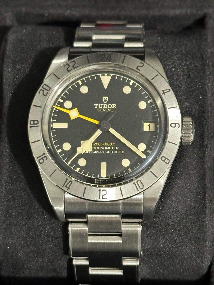 A tudor watch with a black face and yellow hands