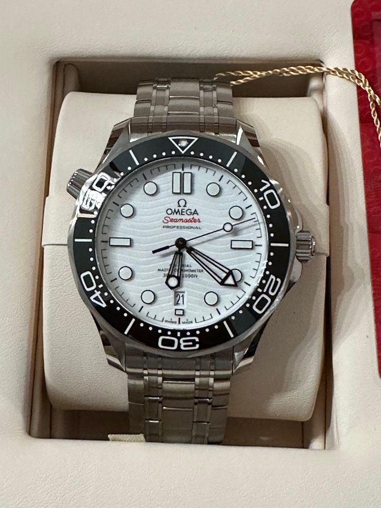 A silver and black omega watch is in a box