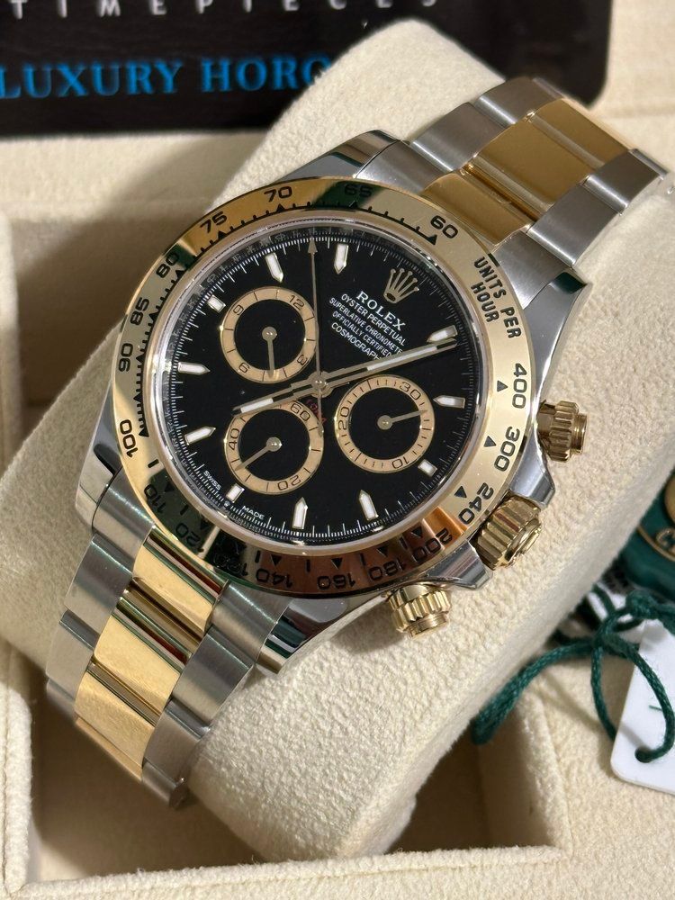 A silver and gold rolex watch is sitting on a white cushion.