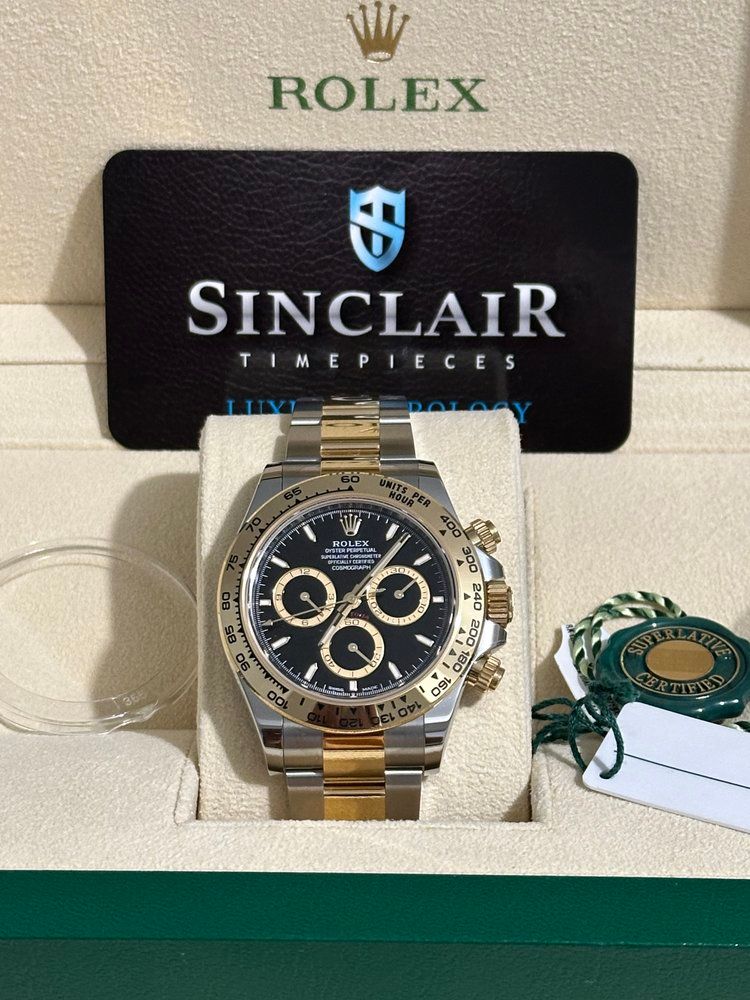 A rolex watch is in a box next to a sinclair timepieces card