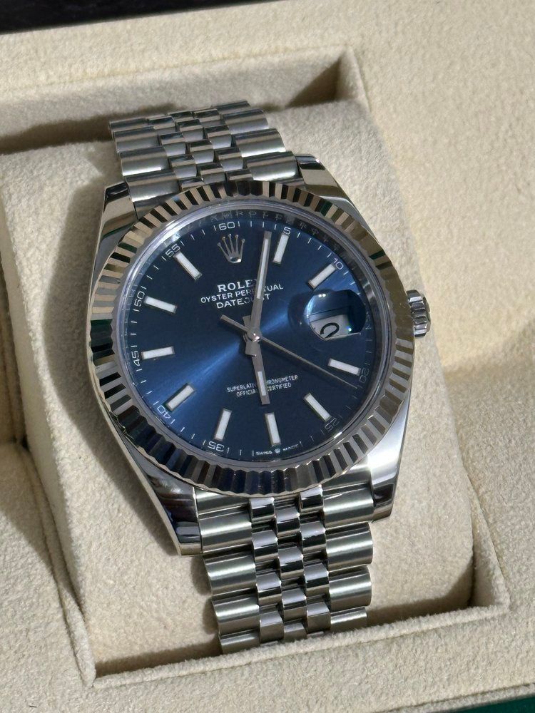 A silver rolex watch with a blue face