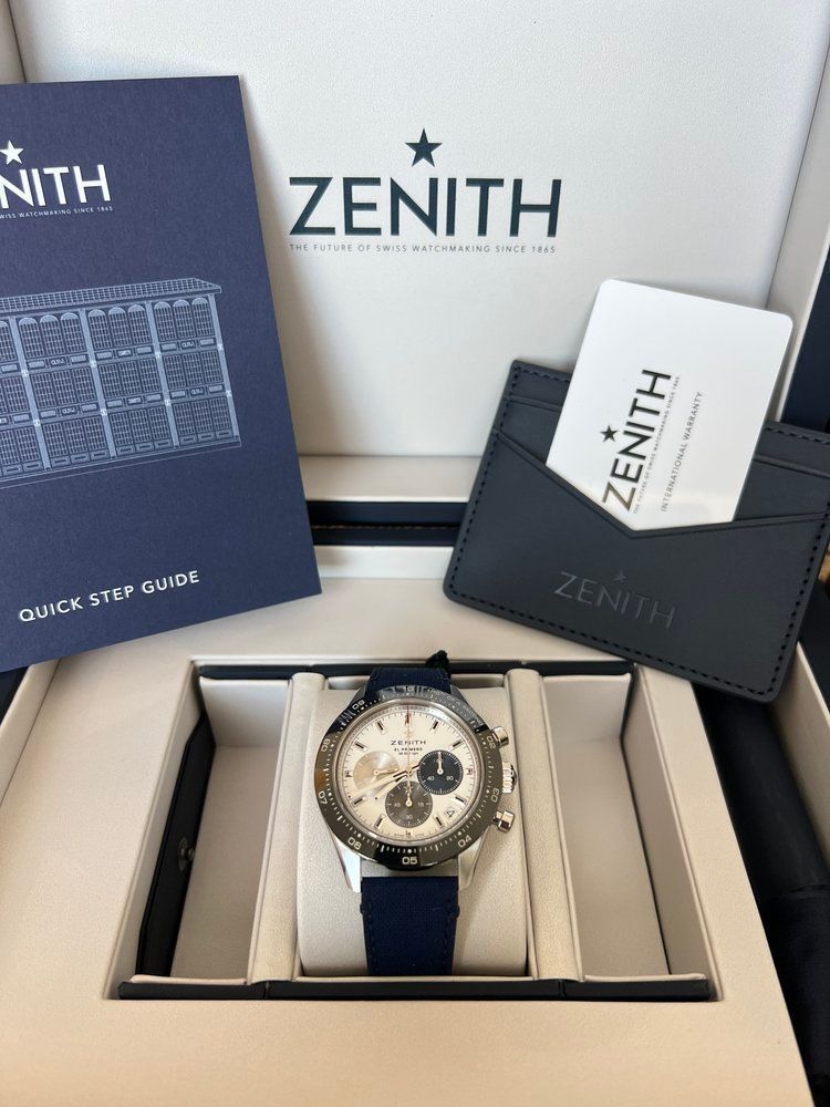 A zenith watch is in a box with a card and instructions