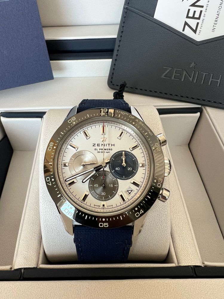 A zenith watch with a blue band is in a box