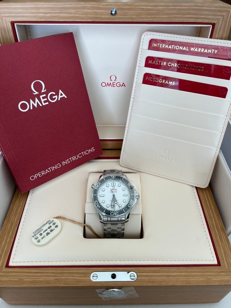 A omega watch is in a wooden box with a certificate and wallet.
