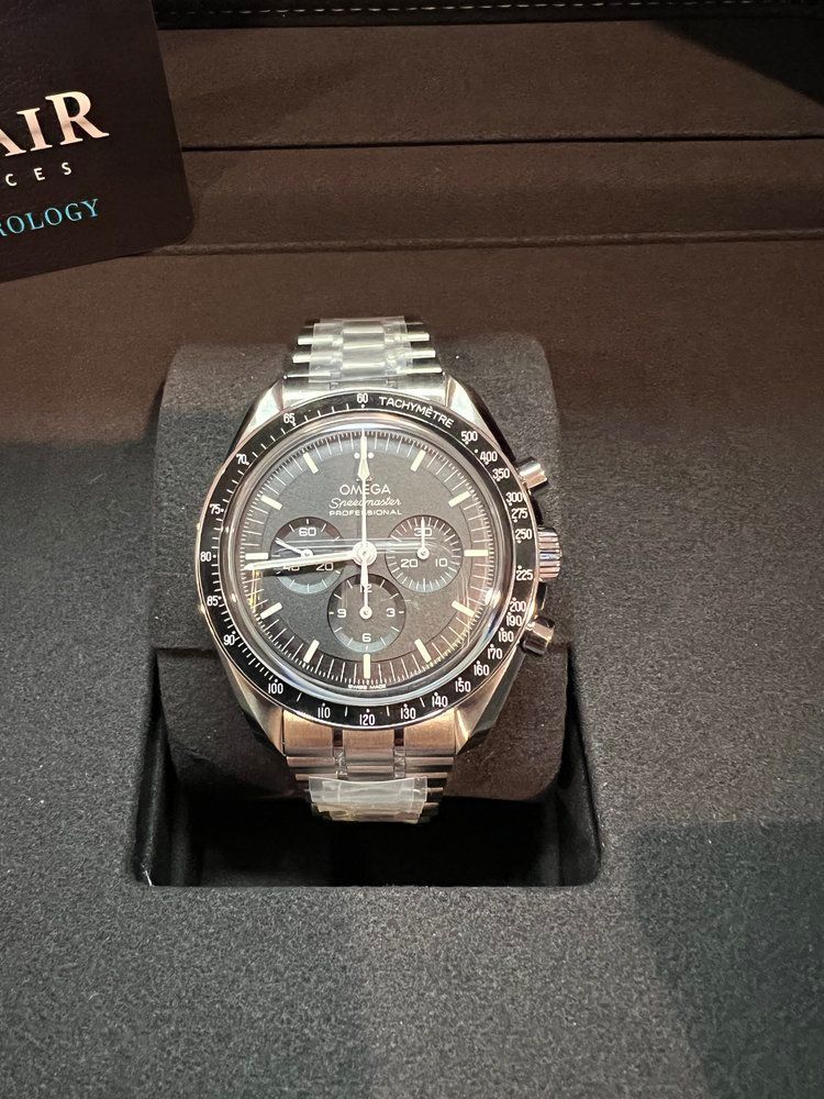 A silver watch with a black face is in a box