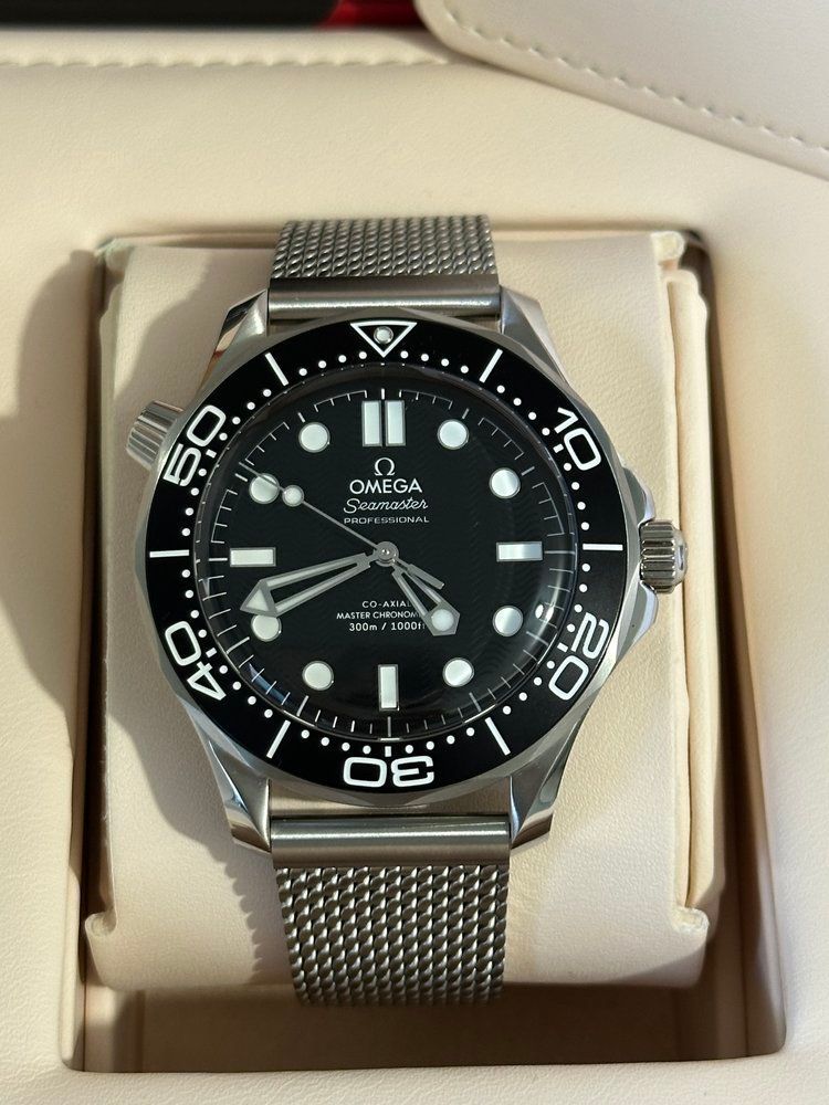 A omega watch is sitting on a white cushion
