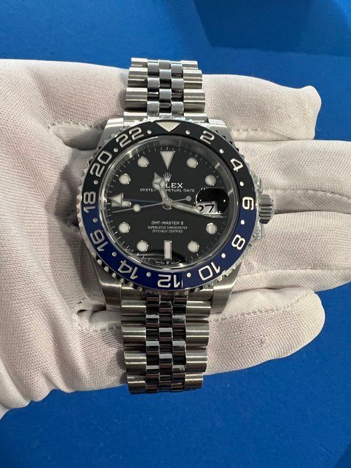 A person is holding a rolex watch in their hand.