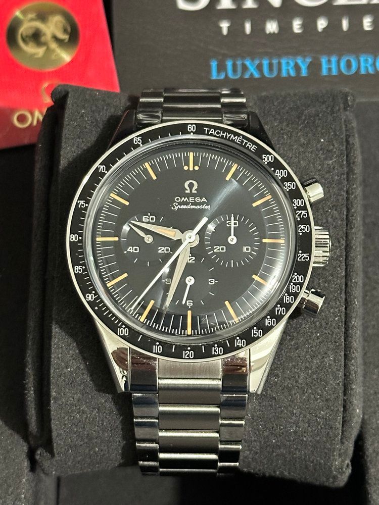 An omega watch is sitting on a black cushion