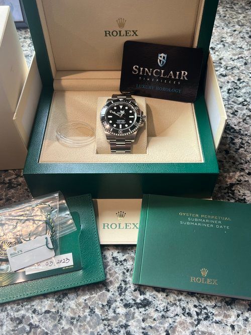 A rolex watch is in a box on a table.